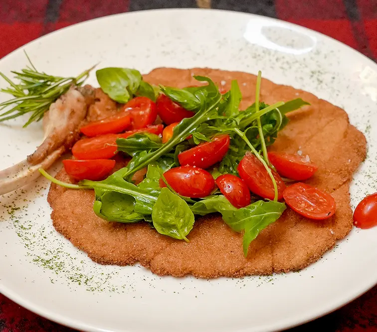 La cotoletta alla milanese coi pomodorini, la rucola e il basilico