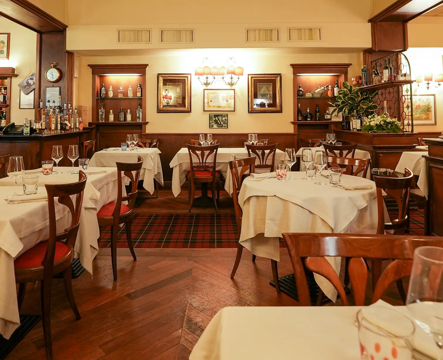La sala coi tavoli dalle tovaglie bianche, le sedie col cuscino rosso, il tartan e le vetrine dei liquori